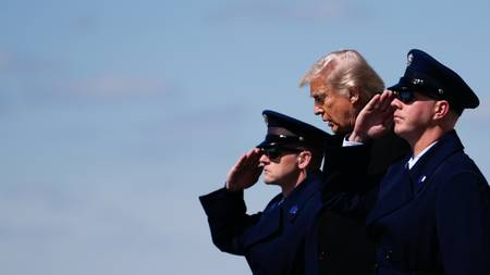 President Donald Trump salutes alongside two airmen. They are all wearing uniforms and hats. The sky is clear and blue in the background. (Bildebeskrivelsen er laget av en KI-tjeneste)